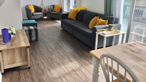 A cozy living room with a grey sofa, yellow cushions, a wooden coffee table, and a side table with a tray. - Renovated Milford Beach home by Charles Island/Silver Sands Pk (Milford)