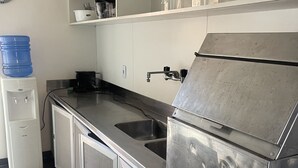 A kitchen with a stainless steel sink, a water dispenser, and a refrigerator. - House 30 meters from Pernambuco Beach (Guarujá)