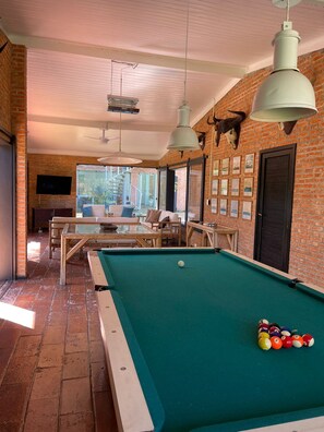 A pool table in a room with brick walls, a ceiling fan, and a mounted bull's head.