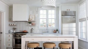 Una cocina moderna con una isla central, electrodomésticos de acero inoxidable y un amplio ventanal que proporciona luz natural.