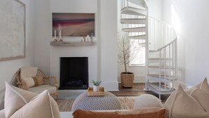 A spacious living room with a fireplace, a large abstract painting, a spiral staircase, and a cozy seating area.