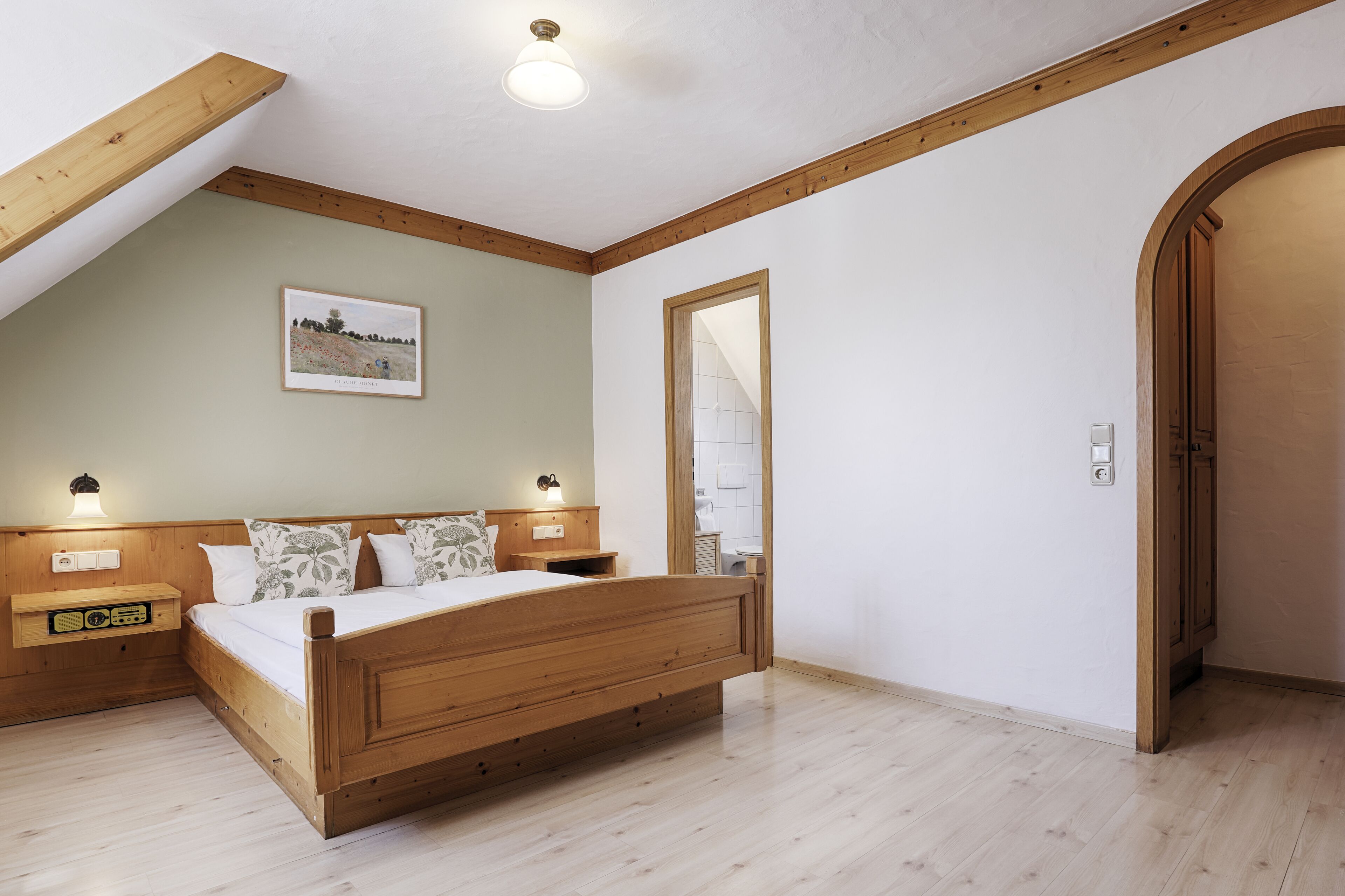 A bedroom with a wooden bed, nightstands, a framed picture, and a large mirror.