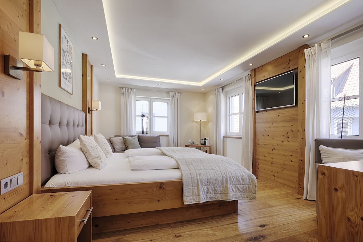 Quarto moderno com cama grande, paredes de madeira e televisão de tela plana.