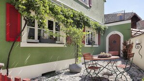 Ein Innenhof mit Steinboden, einem Tisch mit Stühlen und einem Blumentopf.