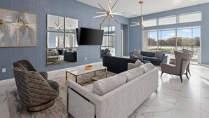 A modern living room with a large sofa, armchairs, a coffee table, and a flat-screen TV. - Premium Home Near Disney w/ Speakeasy Lounge, Theater, Builder Theme BR & Gym (Davenport)