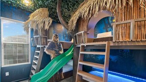 A play area with a slide, climbing net, and shelves. - Grand Home w Karaoke RM, Piggy Playhouse BR, Theater, Arcade & Gym, Near Disney (Davenport)