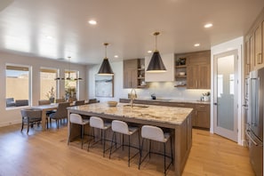 A modern kitchen with a large island, pendant lighting, and wooden cabinets.