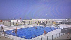 A swimming pool with multiple lanes, surrounded by a fence, and a beach area in the background. - Penthouse 2 Terrassen -oostduinkerke bad (Oostduinkerke)