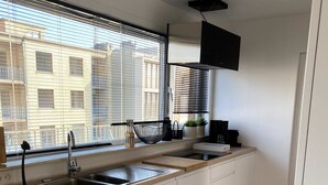 A modern kitchen with a large window, a sink, and a coffee maker. - Penthouse 2 Terrassen -oostduinkerke bad (Oostduinkerke)