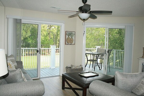 A living room with a ceiling fan, a sofa, a coffee table, and a dining area with a table and chairs. - 1409m 1 Bedroom Condo by Redawning (Calabash)