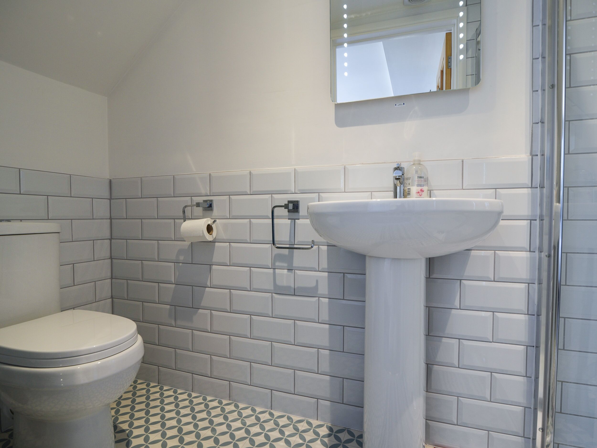 Ein Badezimmer mit Toilette, Waschbecken und einem beleuchteten Spiegel.