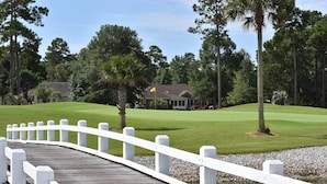 A golf course with a white wooden bridge leading to a clubhouse. - 1409 2 Bedroom Villa by RedAwning (Calabash)