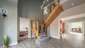 A modern interior with a wooden staircase leading to a loft area, a grey living room with a sofa, and a dining area with a table and chairs. - Appletrees (8), Burnham Market, Norfolk (Burnham Market)