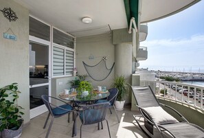 Ein Balkon mit Tisch, Stühlen, Topfpflanzen und Blick auf den Yachthafen.