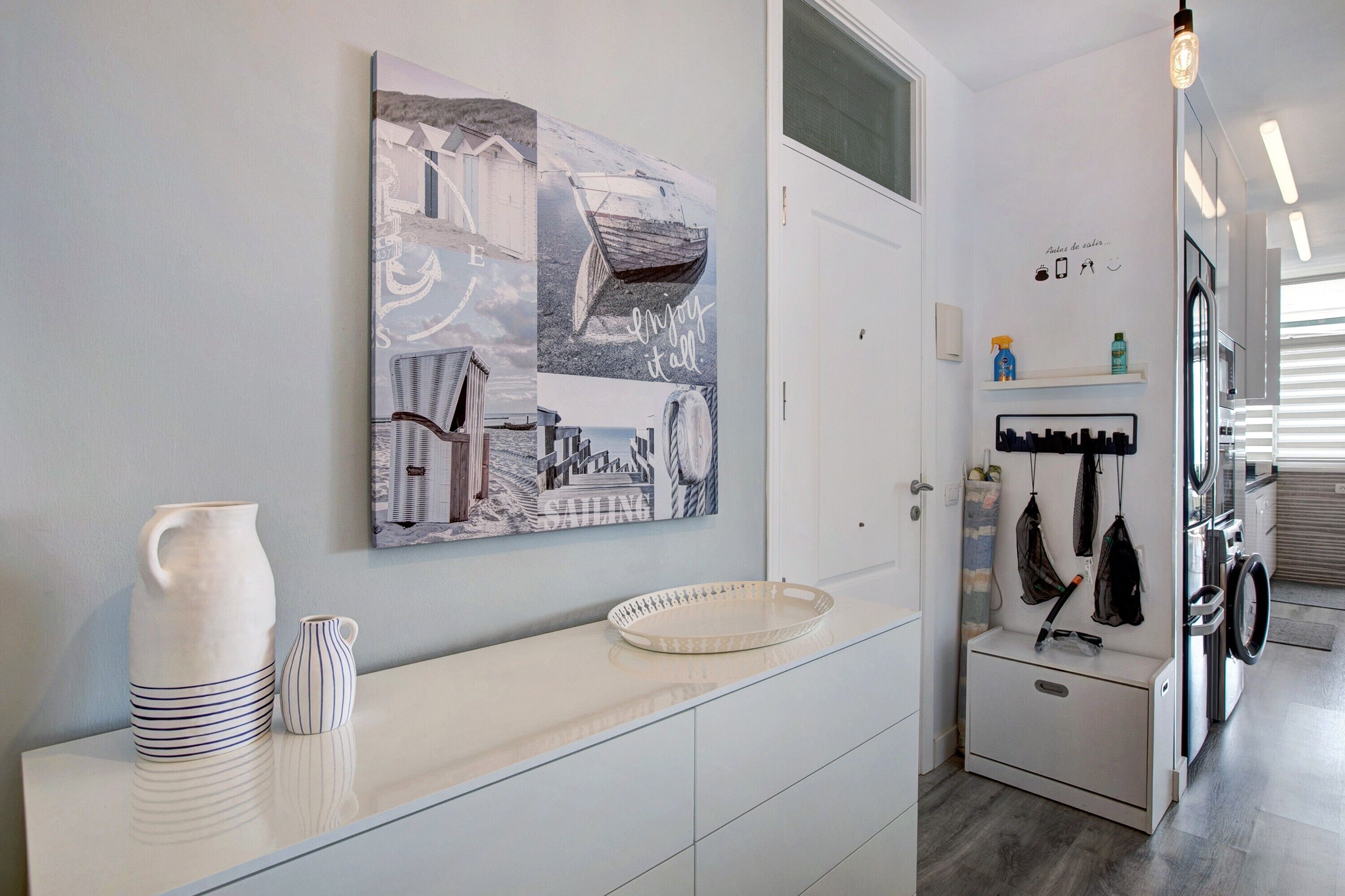 Een moderne keuken met een wit aanrecht, een groot kunstwerk aan de muur en een wasruimte met een wasmachine en droger.
