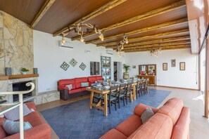 Ein geräumiger Wohnbereich mit Kamin, einem Esstisch für sechs Personen und einem großen Sofa.
