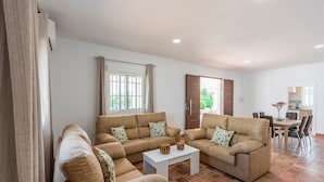 A living room with two sofas, a coffee table, and a dining area with chairs and a table. - Villa "Casa Brisa del Valle" with Private Pool, Covered Terrace & Wi-Fi (Sevilla)