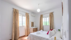 A bedroom with a bed, a dresser, a mirror, and a bottle of champagne on a table. - Villa "Casa Brisa del Valle" with Private Pool, Covered Terrace & Wi-Fi (Sevilla)