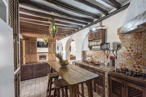 Una cocina con mesa de madera, luces colgantes y salpicadero de azulejos.
