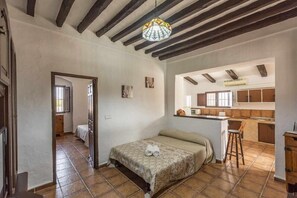 A bedroom with a bed, a small desk, a chair, and a kitchenette.