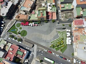 Eine Luftaufnahme eines Stadtblocks mit Gebäuden, Straßen und einem zentralen, begrünten Platz mit Sitzbereichen.