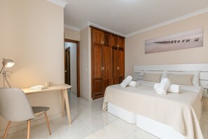 A bedroom with a bed, a desk, a chair, a wardrobe, and a painting on the wall.