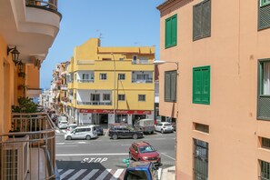 Straßenansicht mit mehrstöckigen Gebäuden, einem sichtbaren Geschäft mit Beschilderung und geparkten Autos.