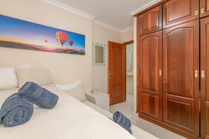 Un dormitorio con cama, un cuadro de globos aerostáticos, armario de madera y un espejo en la pared.