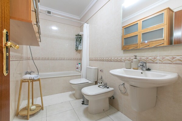 Ein Badezimmer mit Badewanne, Toilette, Bidet, Waschbecken und einem Holzschrank.