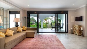 Un salon avec un canapé, un tapis, un téléviseur et une vue sur l’extérieur.