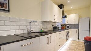 A modern kitchen with white cabinets, a black countertop, and a stainless steel sink. - Bahari (Lyme Regis)