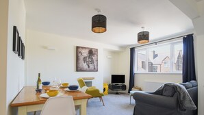 A modern living room with a dining area, a grey sofa, and a TV. - Bahari (Lyme Regis)