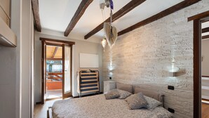 A bedroom with a bed, a brick wall, a wooden ceiling, and a window.