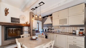 A kitchen with a wooden table, white cabinets, and pendant lights.