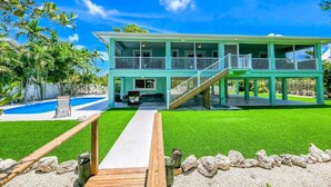 A two-story house with a pool, a covered patio, and a well-maintained lawn. - Pozitively Bliss updated 3bed/2bath single family home near Sombrero Beach with private pool & dockage (Marathon)