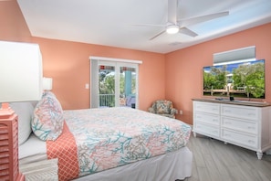 Une chambre à coucher avec un lit, une commode, un ventilateur de plafond et un téléviseur.