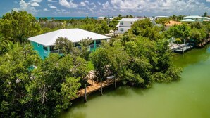 A coastal property with a house surrounded by dense greenery and a dock extending into a greenish water body. - Pozitively Bliss updated 3bed/2bath single family home near Sombrero Beach with private pool & dockage (Marathon)