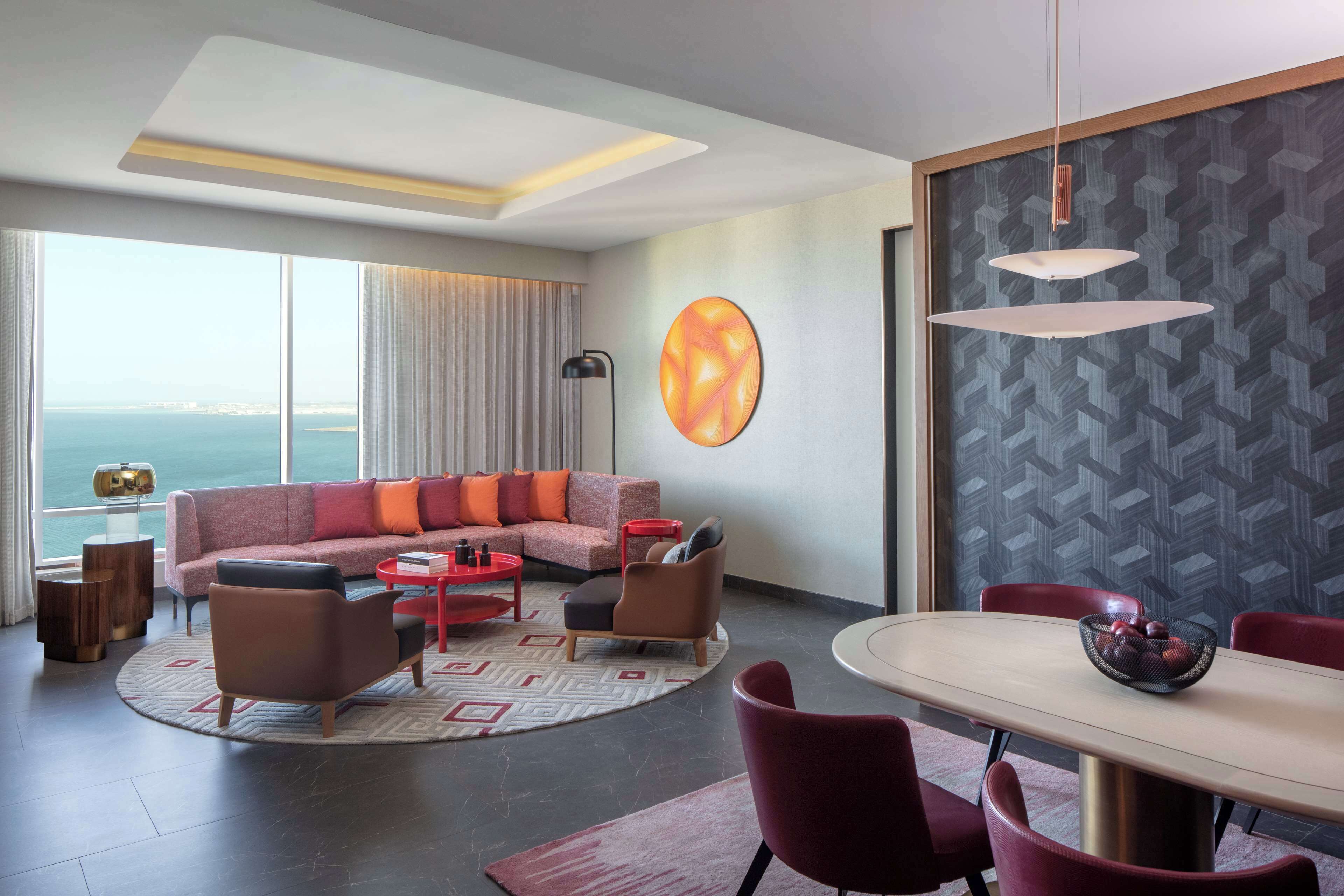 Una sala de estar moderna con un sofá grande, una mesa de comedor y vista al mar.