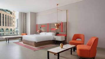 Habitación de hotel moderna con una cama grande, un escritorio, dos sillas y vistas a la ciudad.