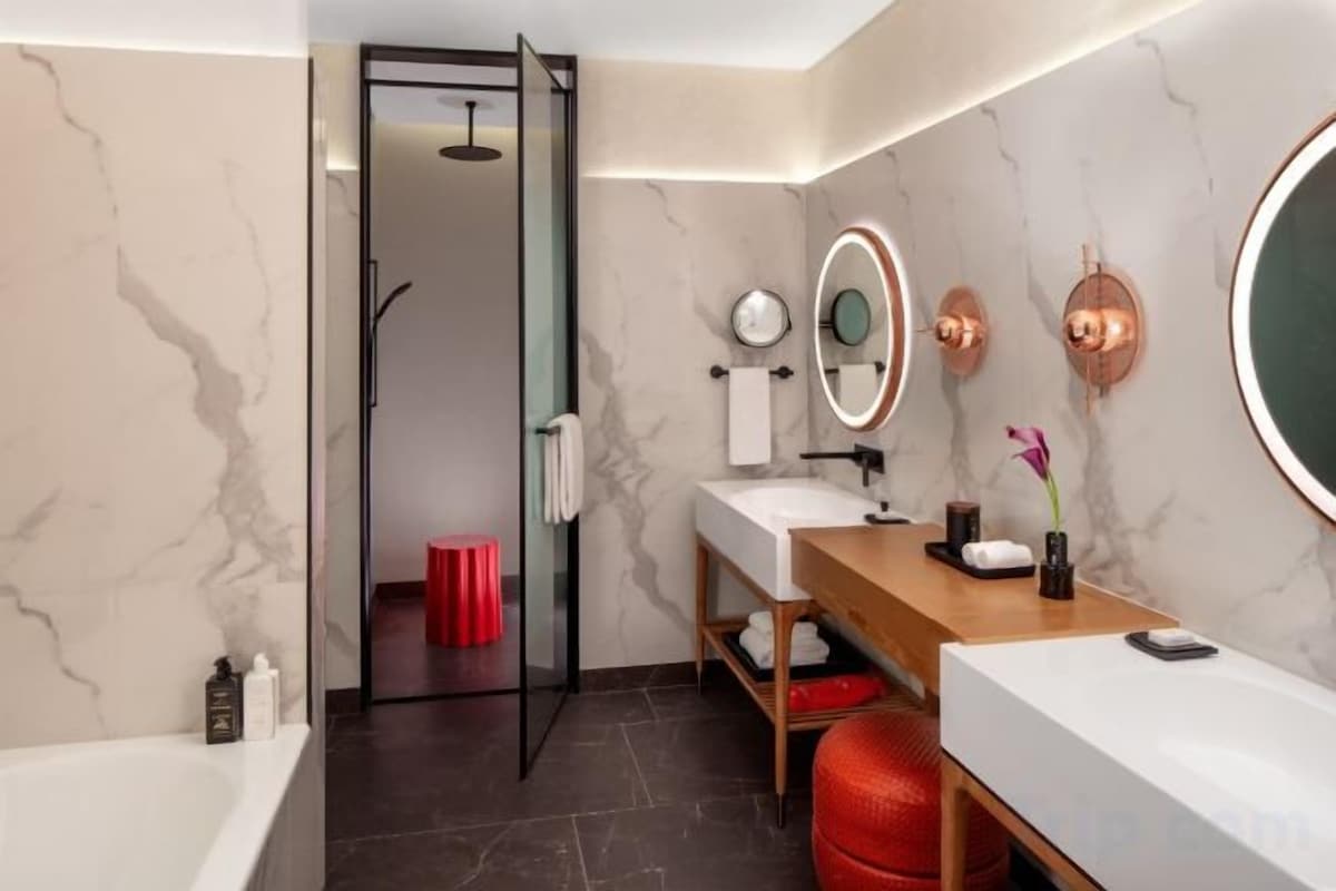 A modern bathroom with a glass shower door, a wooden vanity, a white sink, and a large mirror.