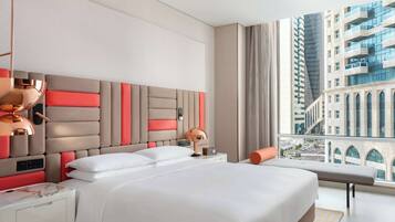 Een moderne hotelkamer met een groot bed, een nachtkastje, een lamp en uitzicht op een hoog gebouw.