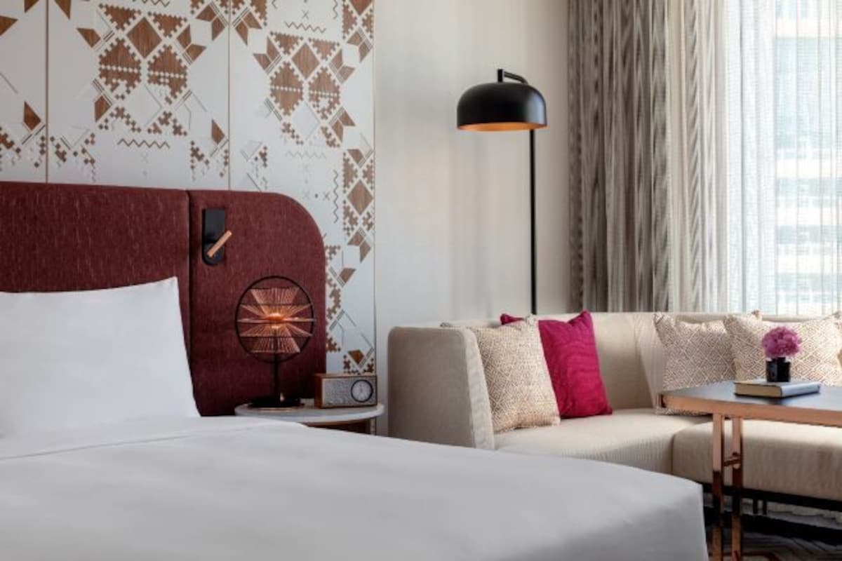 Une chambre d’hôtel avec un grand lit, un canapé, une petite table, une lampe et une radio.