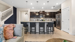 A modern kitchen with a central island, dark wood cabinets, stainless steel appliances, and pendant lighting. - PROMO Beautiful 5 BR Home,Private Pool,Resort - by Blue Sky Villas (Davenport)