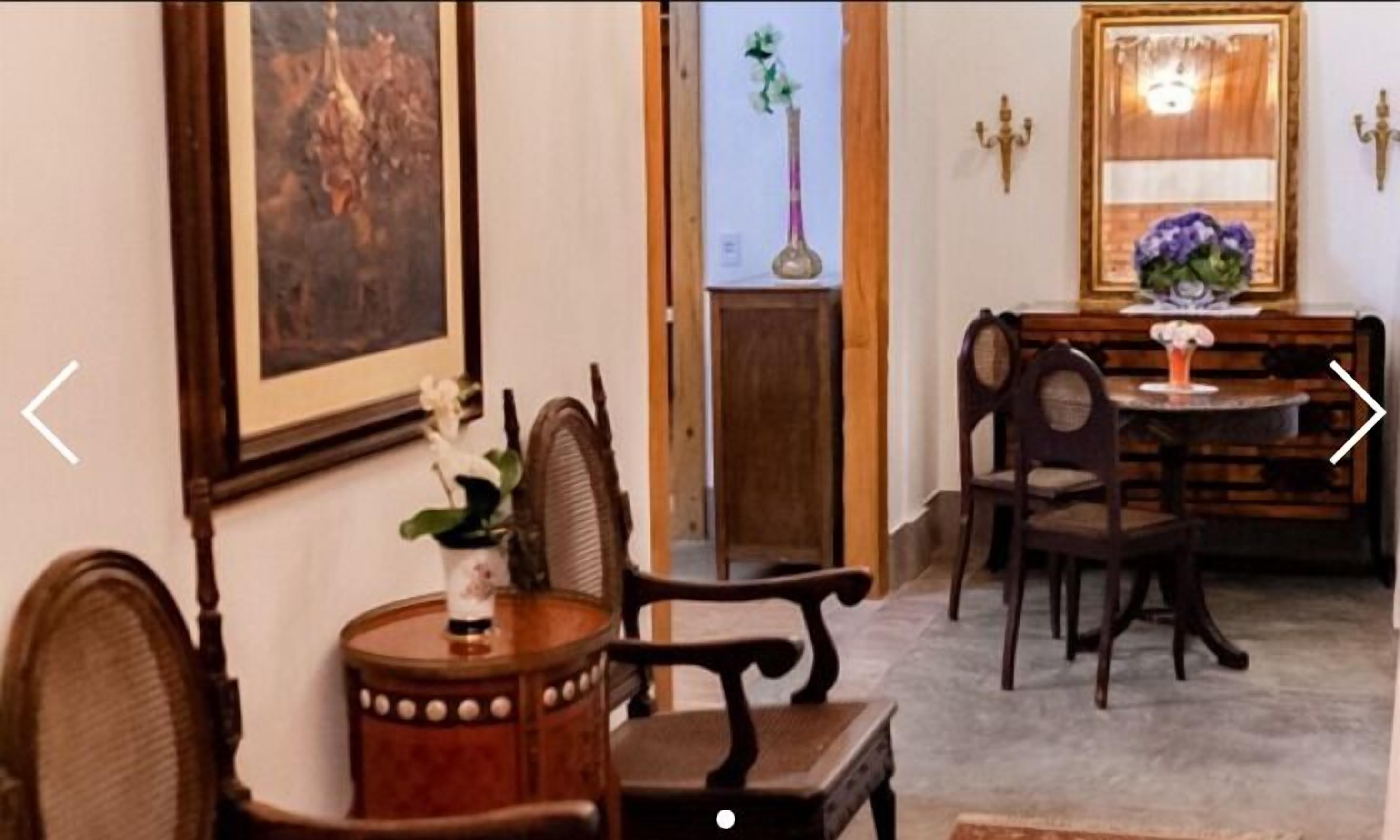 A dining area with wooden furniture, a vase with flowers, and a framed picture on the wall.