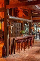 Un interior rústico con vigas de madera, una zona de bar con taburetes y adornos de asta de ciervo.