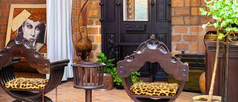 A room with two wooden chairs with leopard print cushions, a small round table, and a decorative door with a mirror.