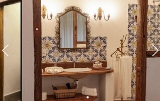 Un baño con un espejo antiguo, un lavamanos y un perchero para toallas.