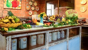 Una encimera de cocina con diversas frutas y verduras, una ventana y una pared de ladrillo.
