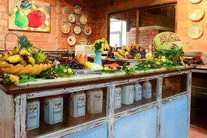 Una encimera de cocina con diversas frutas y verduras, una ventana y una pared de ladrillo.