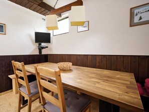 Ein Holzespeisesaal mit vier Stühlen, einem Fernseher und einer Wandleuchte.
